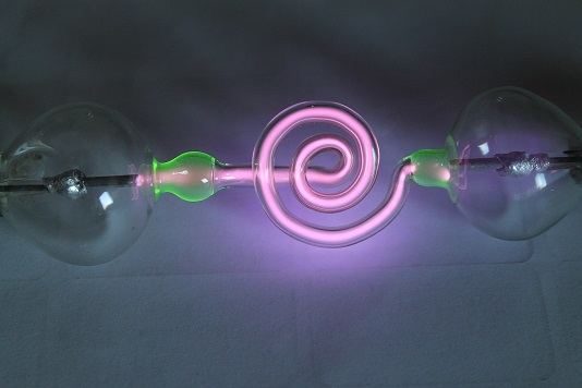 Figure 10 — A Geissler tube glowing on the bench, struck by the tester's EHT used as a variable high-voltage source. The rarefied gas fluoresces in a colour set by the fill; some have internal phosphor coating…